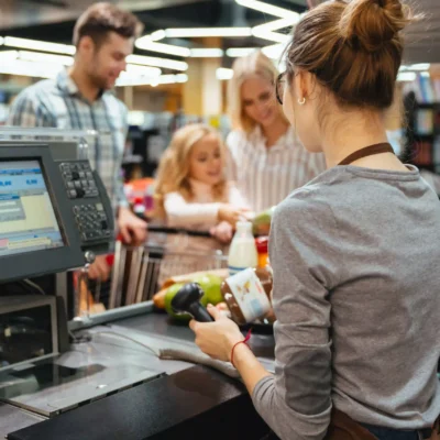 Cajera de supermercado en Tenerife atendiendo a clientes y cobrando en la caja registradora.